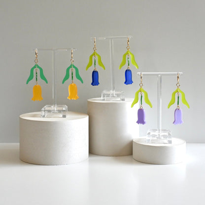 Tulip Market Huggies in marigold, cobalt blue, and lavender, with green acrylic leaves, beaded stems, and ribbed tulip drops on gold huggie hoops.